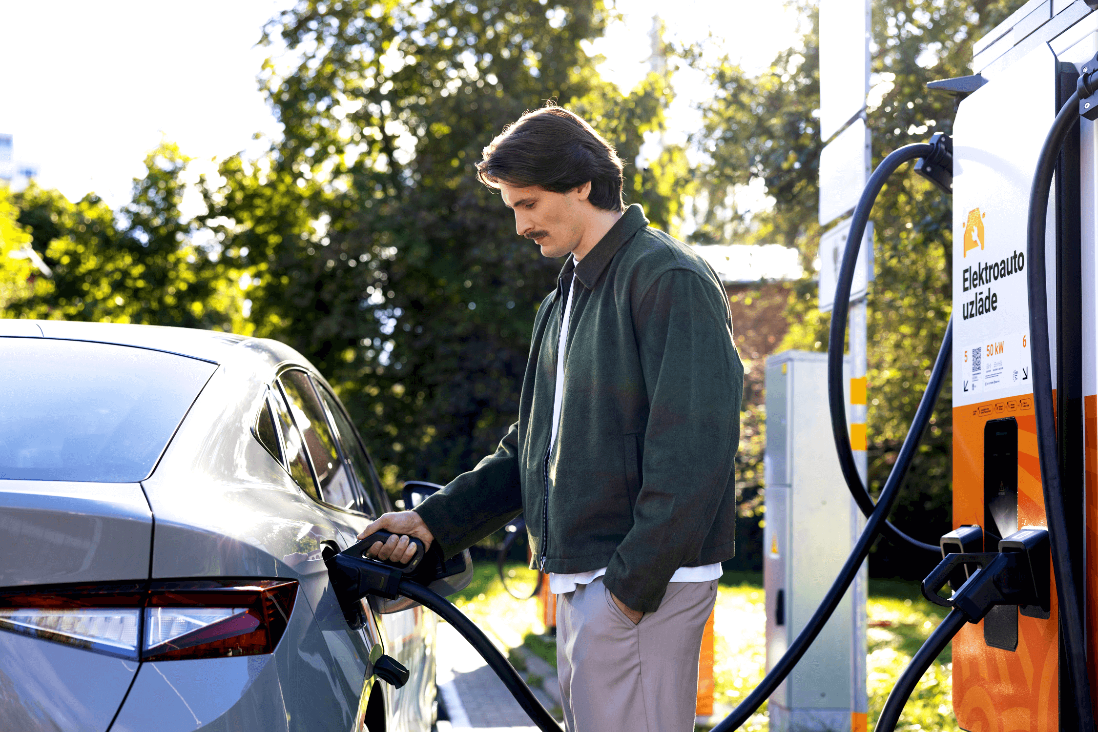 A man connects an electric car to an Elektrum Drive fast-charging station.