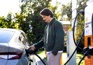 Vīrietis lādē automašīnu pie Elektrum Drive uzlādes stacijas