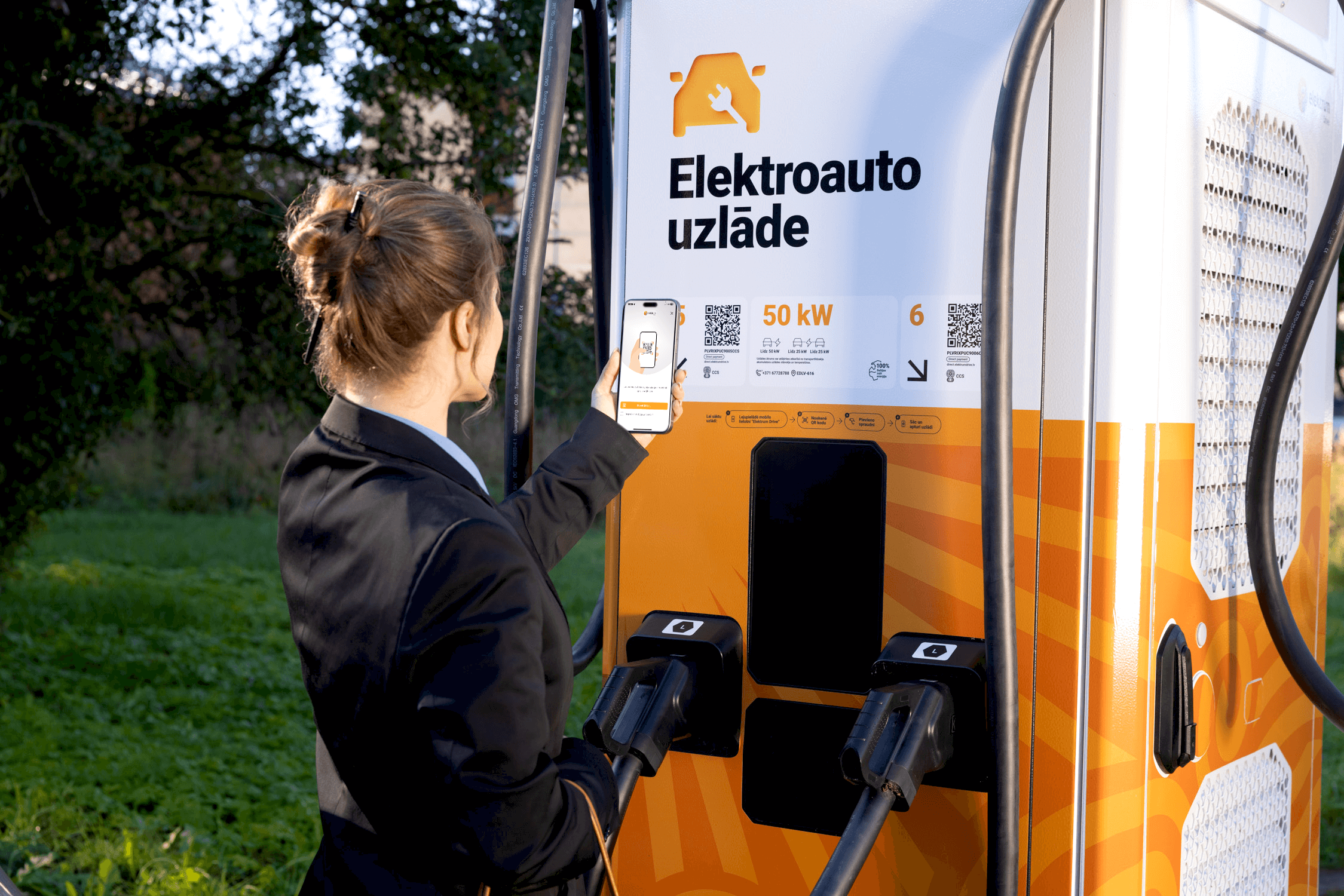 A woman activates the electric vehicle charging station by scanning the QR code on the station with her smartphone.